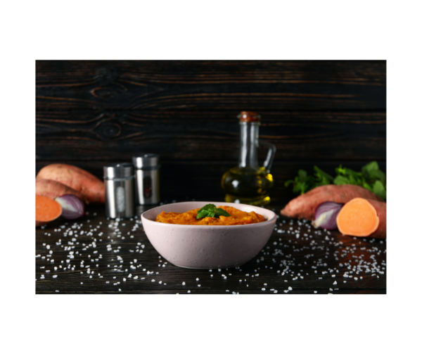 bowl of sweet potato puree soup on granite counter top, salt and pepper shakers