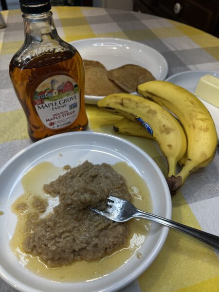 beginner recipe of puréed banana pancakes, bottle maple syrup, bunch of bananas, Puréed bananas in  pancakes on a saucer with fork resting on the plate