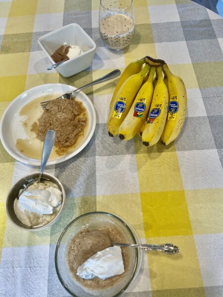 beginner puréed banana recipes made in five different bowls of food lined up on a table along with bunch of bananas 