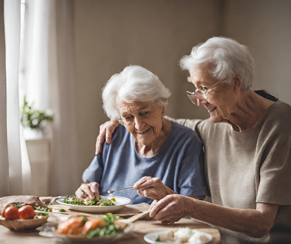 Elderly woman assisting another elderly woman eat her meal by feeding her at the table . Table has plate of food and other dishes full of food 